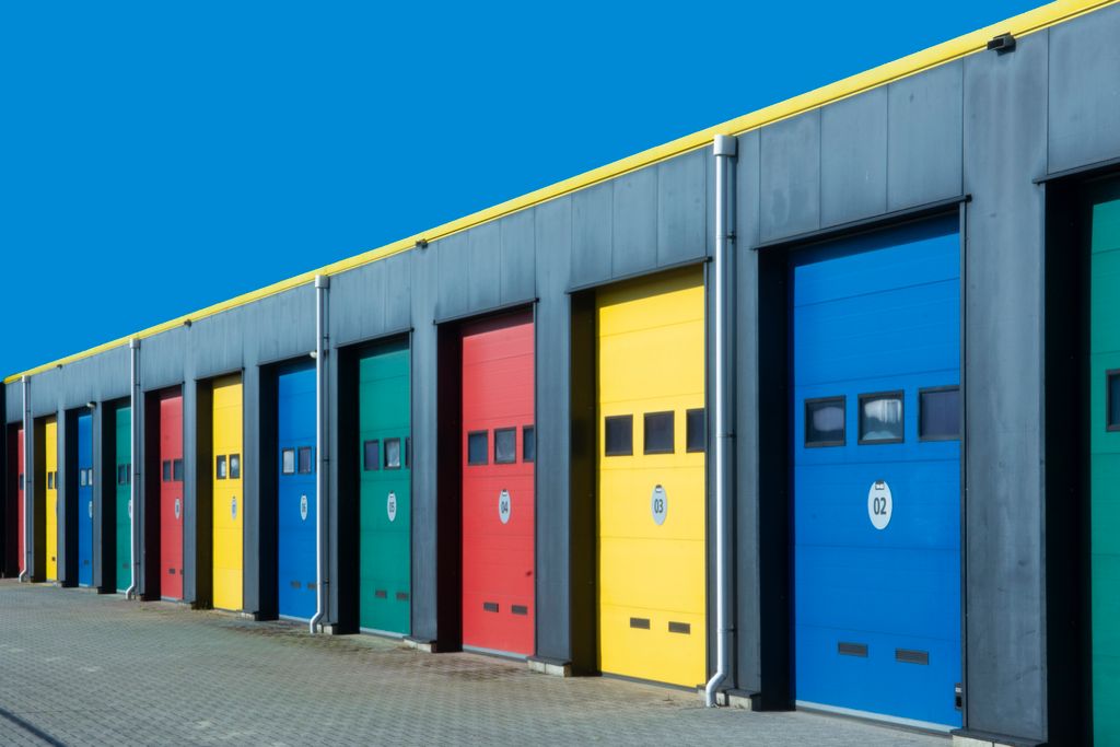 Vibrant row of industrial garage doors in blue, red, yellow, and green, perfect for commercial use.